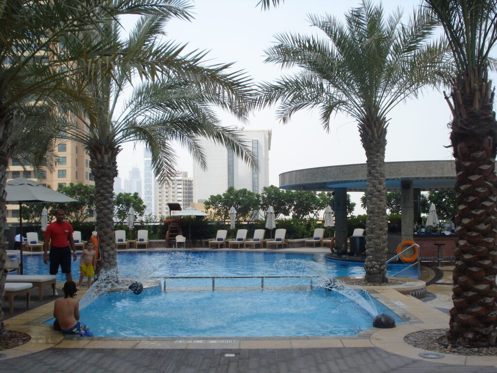 Pool von einem Hotel mit Menschen und Palmen